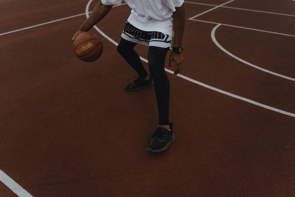 Dynamic shot of a basketball player dribbling on an outdoor court, showcasing athleticism.
